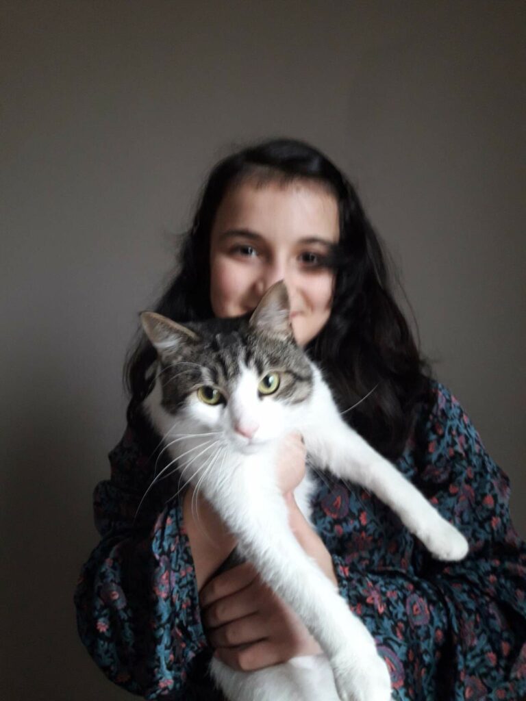 Девушка с тёмными волосами бережно держит бело-серого кота Ёшку на руках